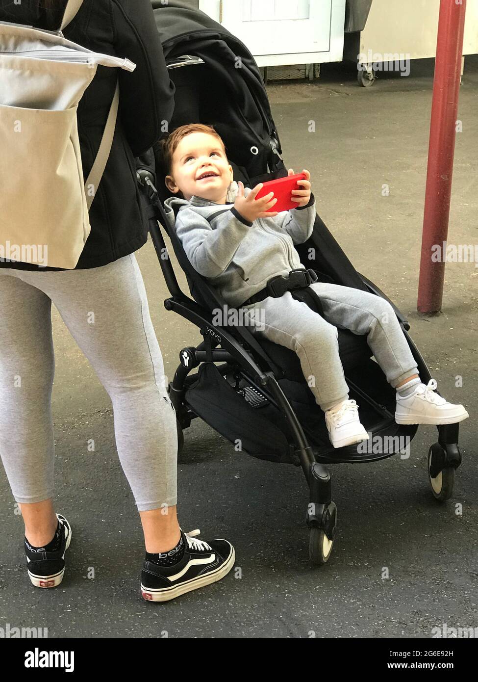 Kleinkind im Kinderwagen mit Handy Stockfoto