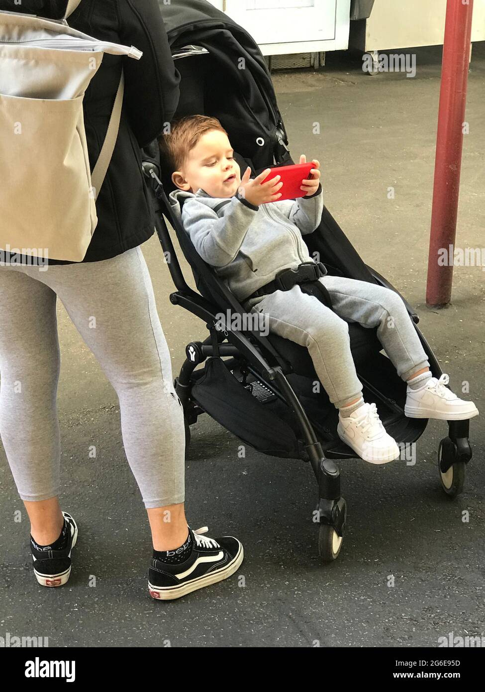 Kleinkind im Kinderwagen mit Handy Stockfoto