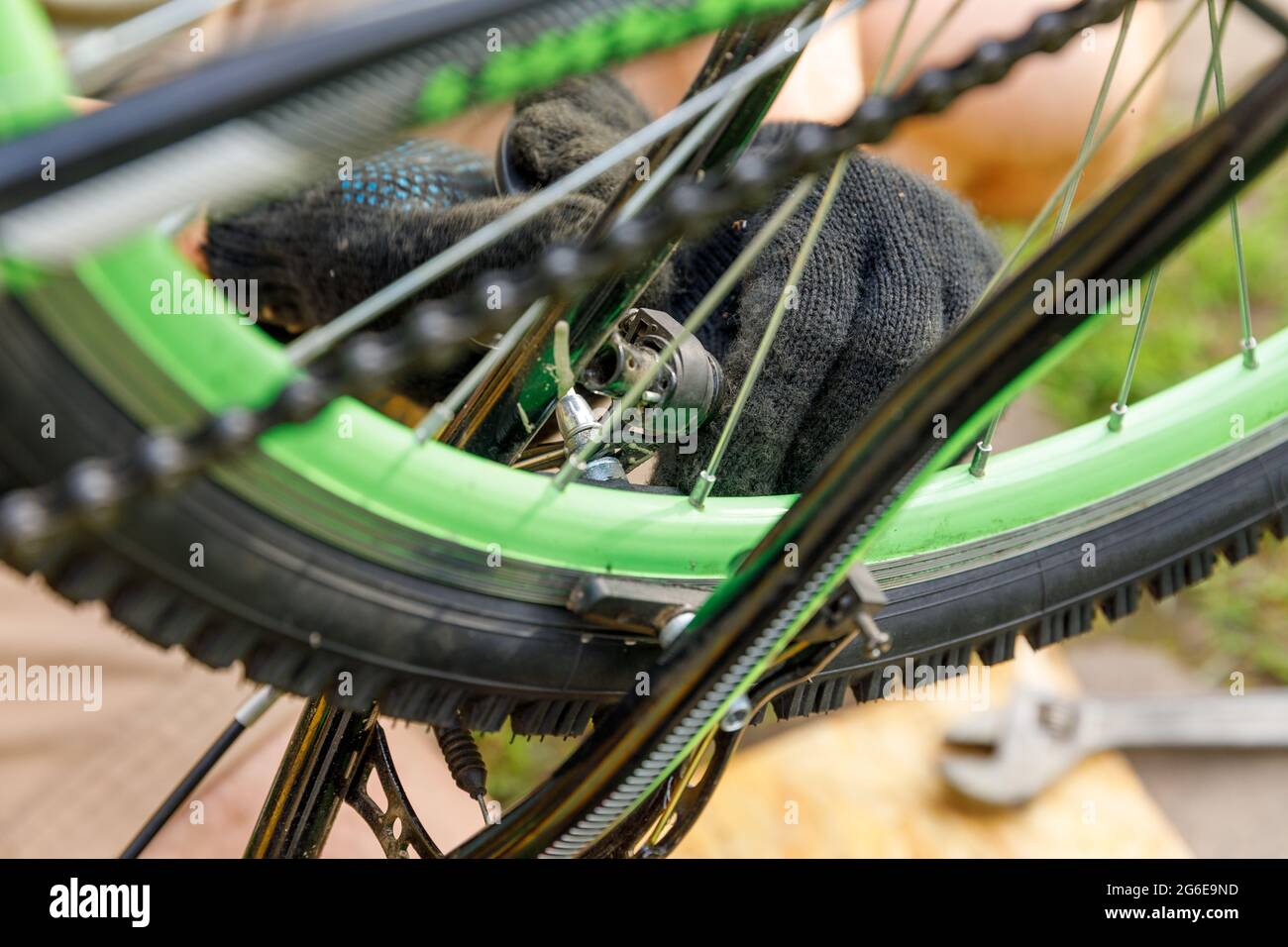 Fahrradmechaniker Mann repariert Fahrrad in Fahrradwerkstatt, im Freien. Die Hand des Fahrradfahrers untersucht, repariert modernes Zyklenübertragungssystem. Fahrrad Stockfoto