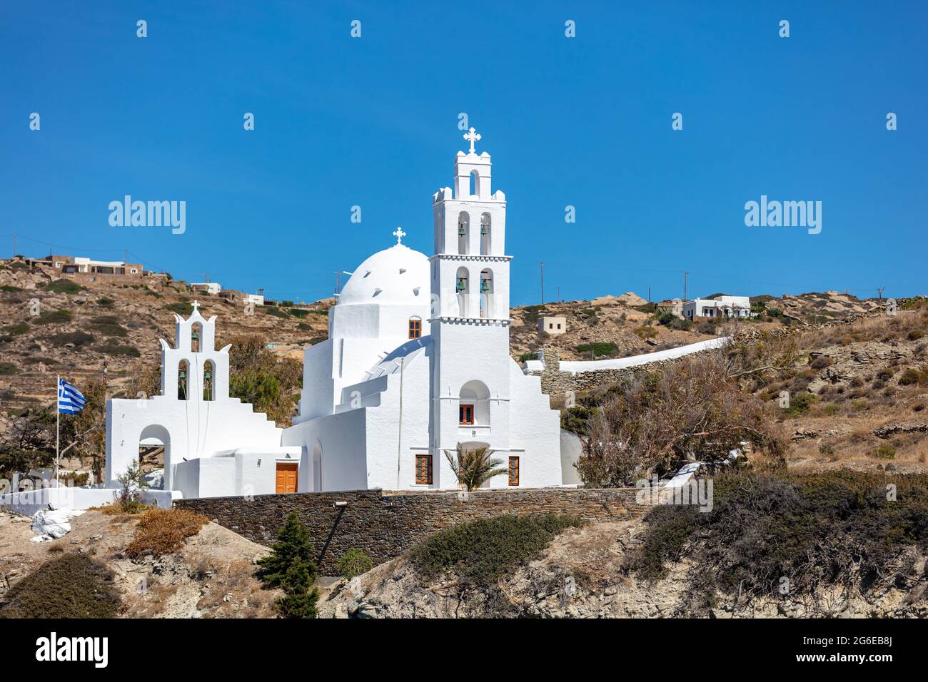 IOS Nios Insel Fassade der Agia Eirini Kirche, Kykladen, Griechenland. Alte weiß getünchte Steinmauer Christian orthodoxen Tempel Kreuz auf oben metallischen Glocke Sommer Stockfoto