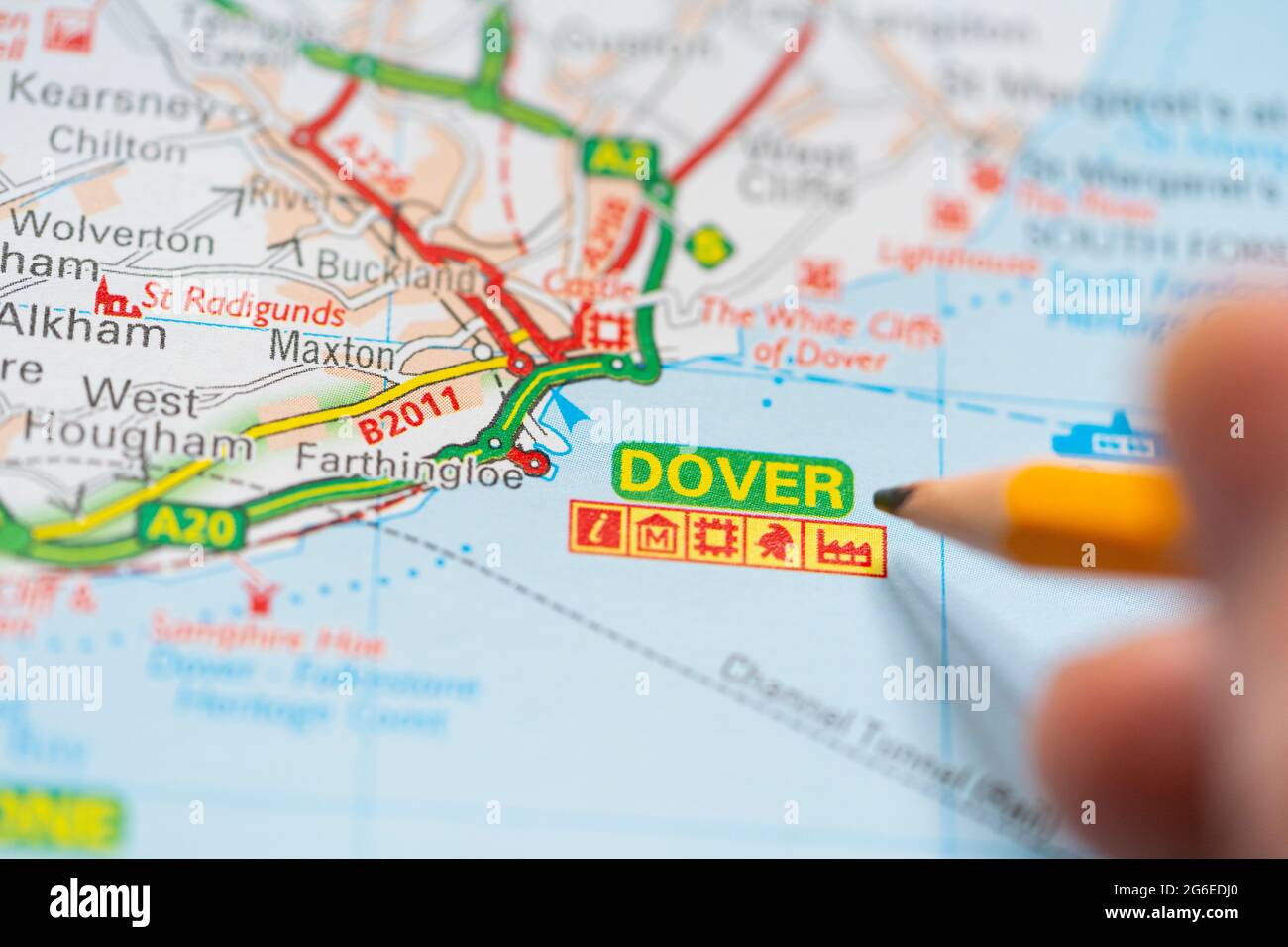 Makro-Nahaufnahme einer Seite in einem gedruckten Roadmap-Atlas mit einer Männerhand, die einen Bleistift hält und auf die Stadt Dover in Kent, England, zeigt Stockfoto