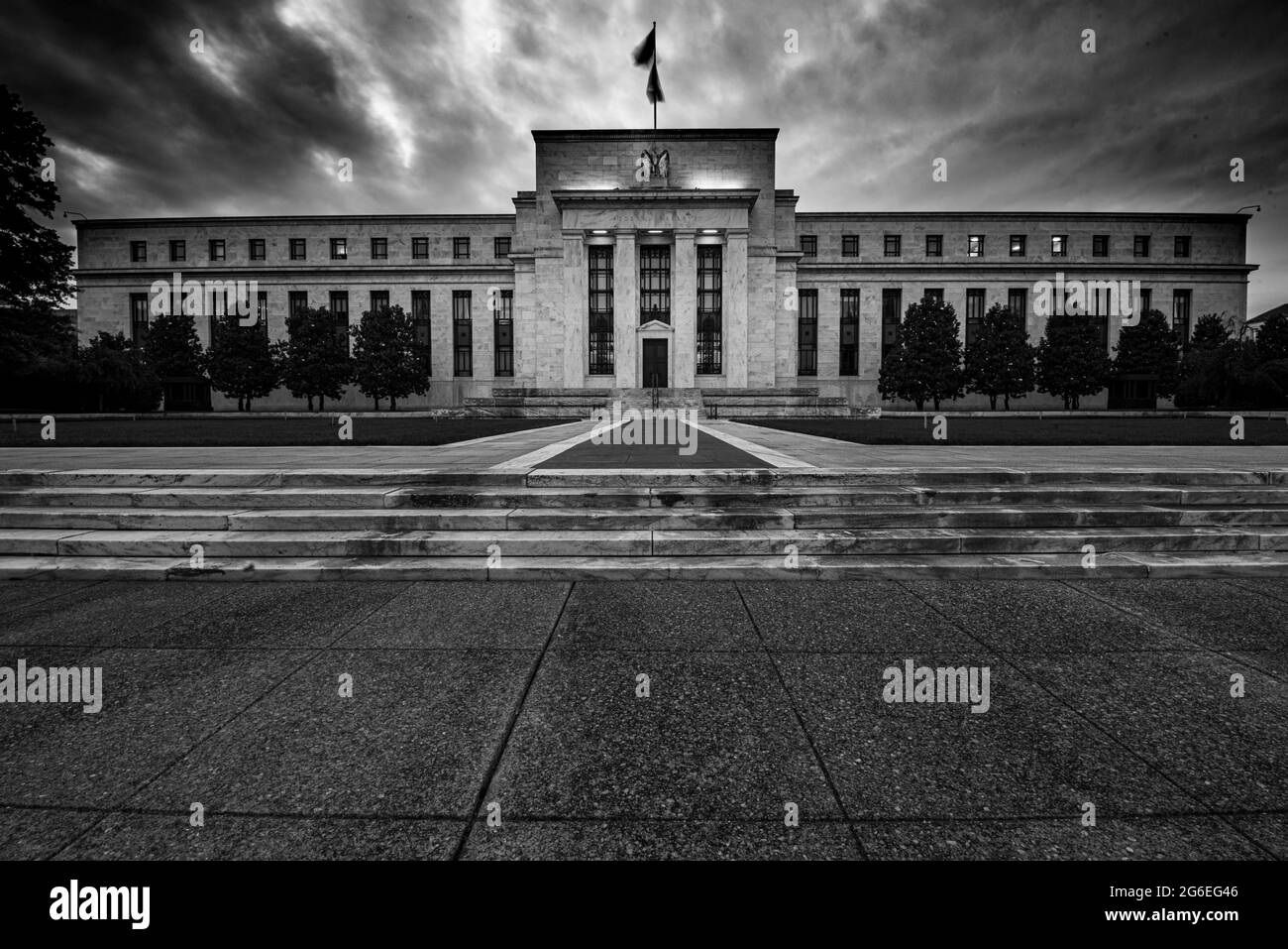 Zeiteinwirkung in Schwarz-Weiß der Federal Reserve Bank in Washington DC mit Wolken im Hintergrund, die ein unheilvolles Bild des Aufsichtsgremiums erzeugen. Stockfoto