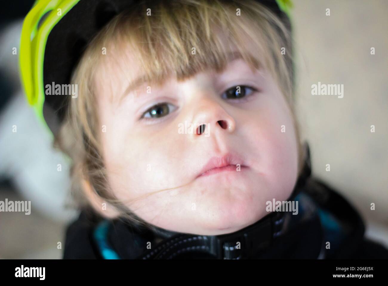 Kleinkind, das sein Push-Bike in einem grünen Helm reißt Stockfoto