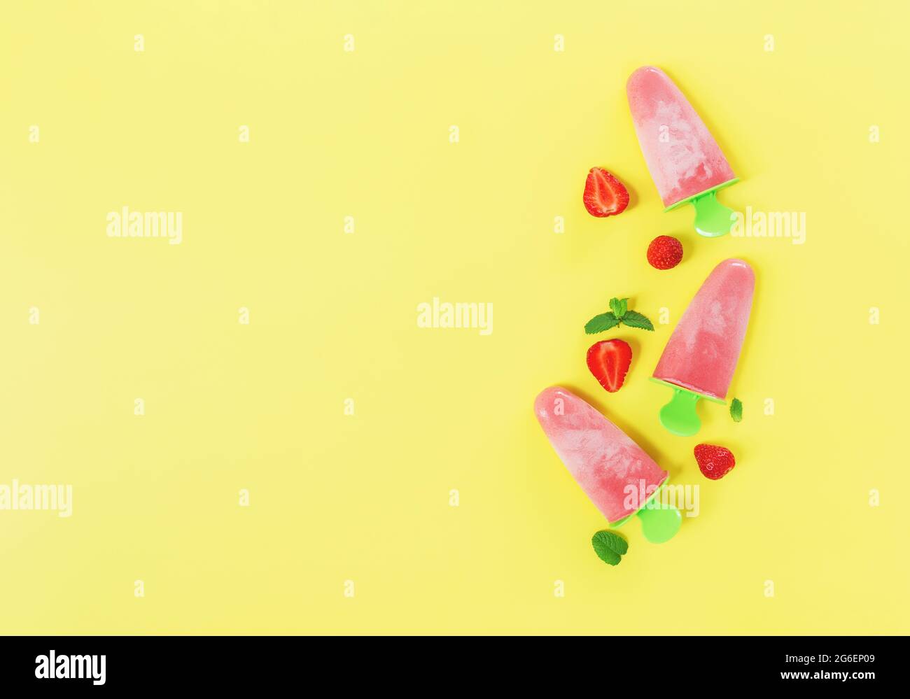 Flaches Lay mit fruchtigem rosa gefrorenem Sorbet Eis auf grüner Plastikstick Sammlung mit Schnitten von Erdbeere, Minzblätter auf gelbem Hintergrund. Gefroren Stockfoto