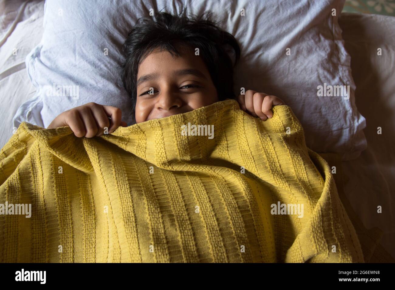 Draufsicht auf einen Jungen im Bett, der mit selektivem Fokus faul aufwacht. Konzept eines faulen Sonntags im Bett. Stockfoto