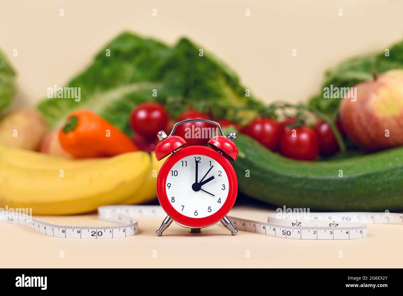 Konzept zum Abnehmen, indem Sie zu bestimmten Zeiten nur gesunde Lebensmittel mit Gemüse, Obst, Maßband und Uhr essen Stockfoto