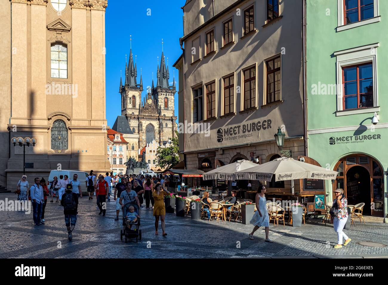 Menschen, die auf der Kopfsteinpflasterstraße als Tyn-Kirche und Staromestske Namesti auf dem Hintergrund in der Altstadt von Prag, Tschechische Republik, spazieren gehen. Stockfoto