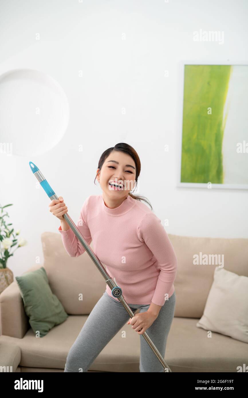 Während der Reinigung der Wohnung, die Frau singt und tanzt, in ihren Händen eine Mop. Stockfoto