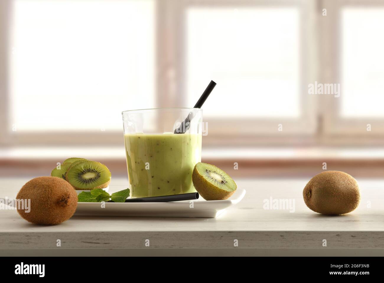 Obst-Frühstück mit einem Glas Kiwi-Getränk auf dem Teller und Container schneiden Obst auf dem Tisch und Fenster Hintergrund. Vorderansicht. Stockfoto