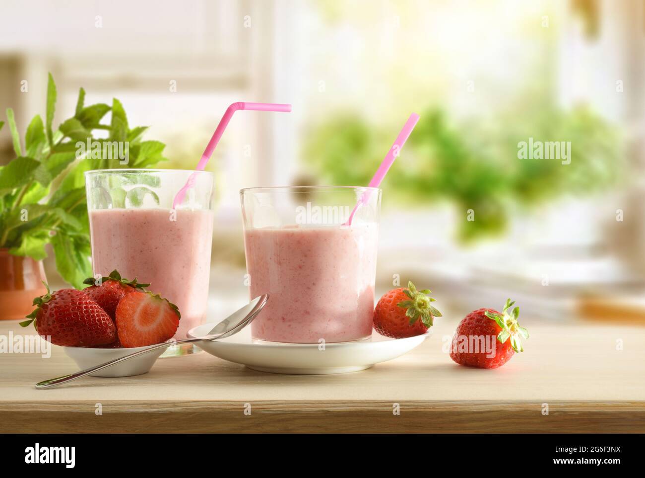 Gläser voller Erdbeer-Smoothie auf einem Holztisch voller Früchte in der Küche. Vorderansicht. Stockfoto