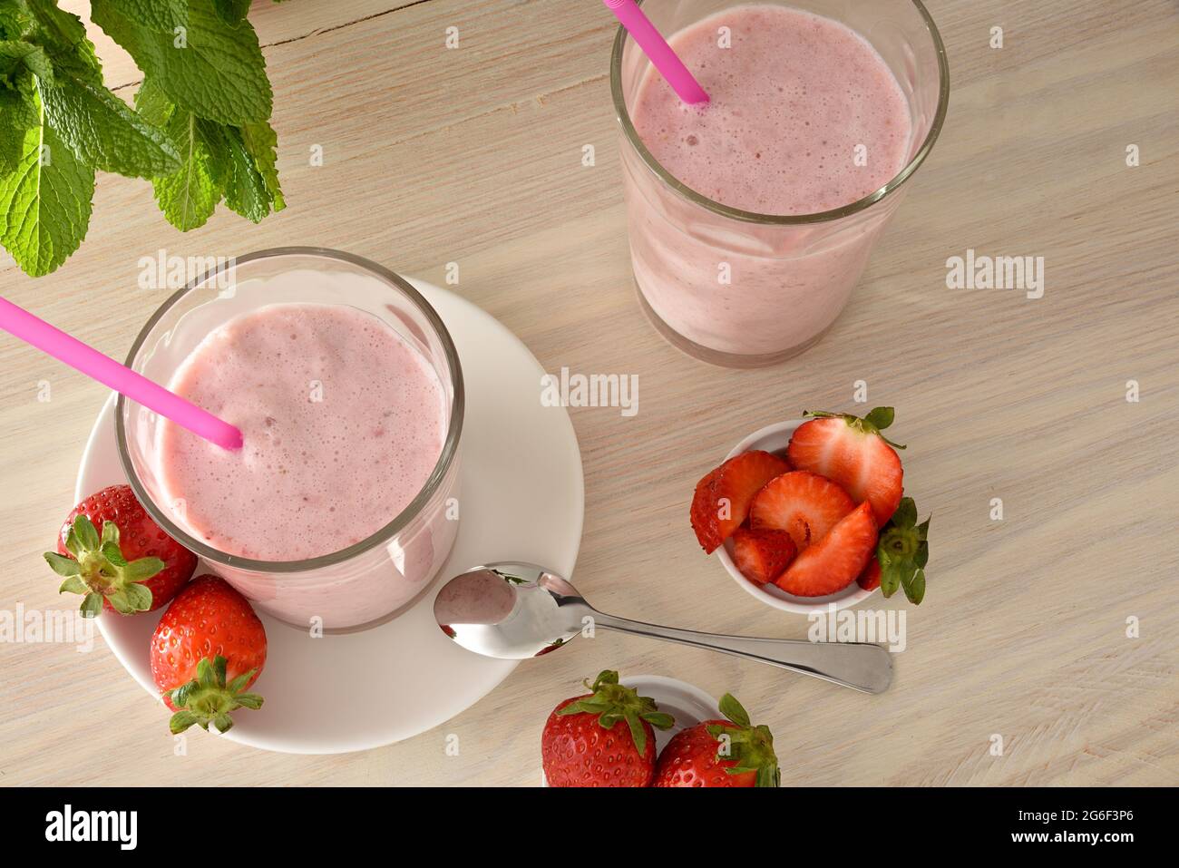 Zwei Gläser Erdbeermilchshake auf einem Holztisch mit Fruchtrezepten. Ansicht von oben. Stockfoto