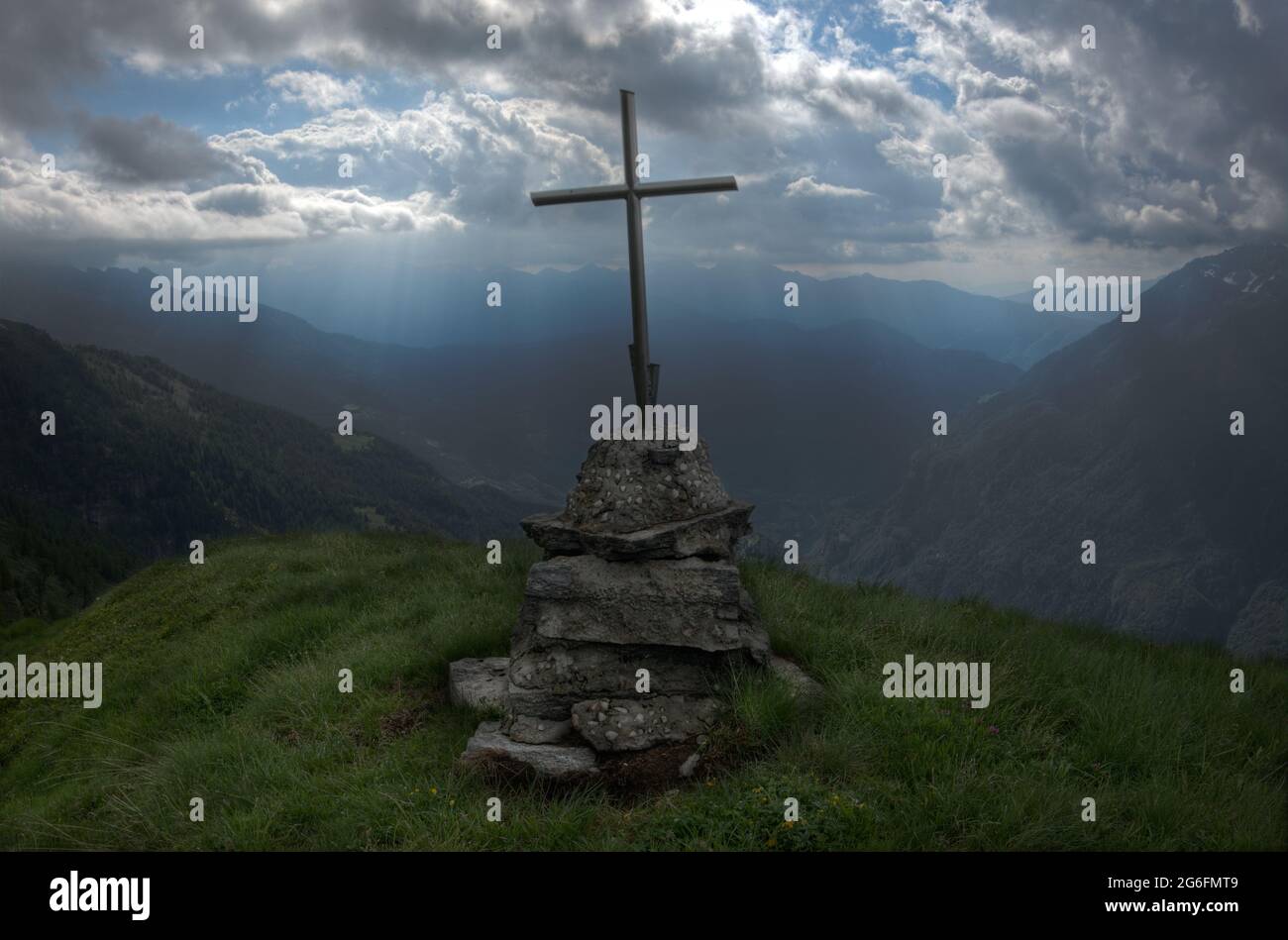 Silhouette des Kreuzes auf dem Berg in den italienischen alpen unter dramatischem Himmel Stockfoto