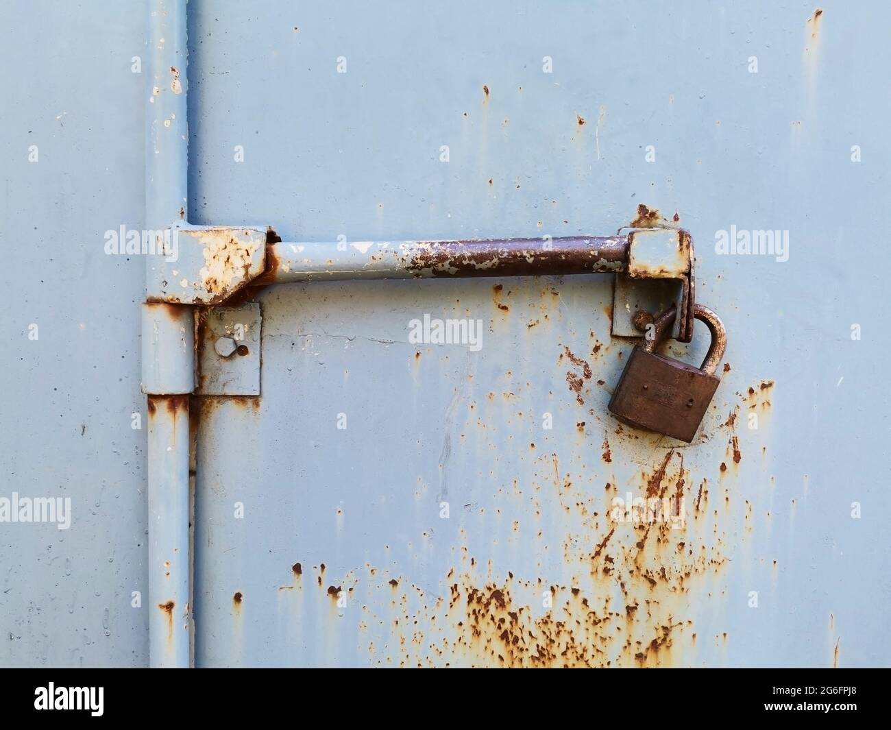 Die verrostete Tür. Das verrostete Vorhängeschloss. Türschloss. Sicherheitsmaßnahmen. Eiserne Tür und Schloss. Stockfoto