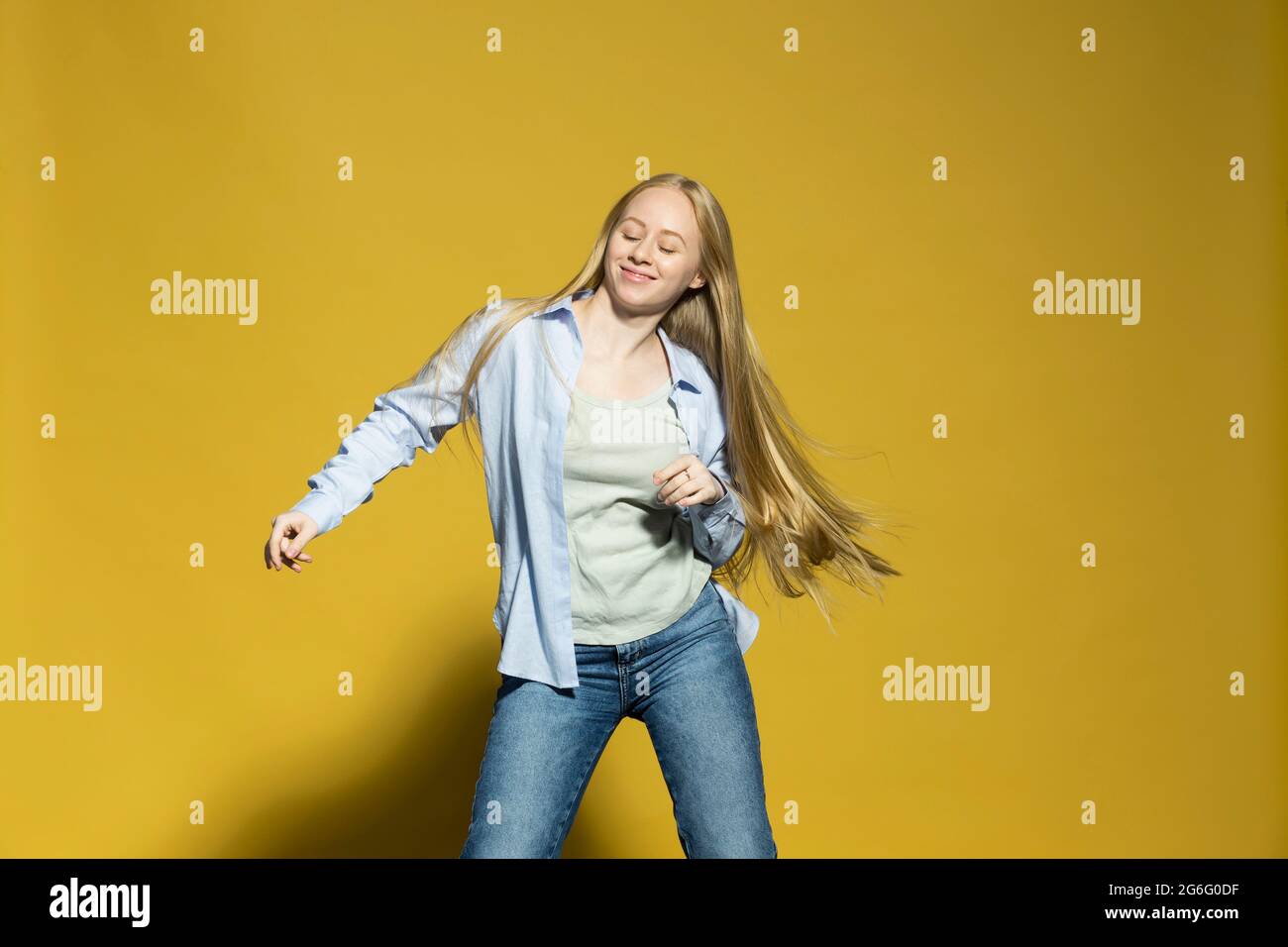 Portrait sorglose junge Frau tanzt auf gelbem Hintergrund Stockfoto