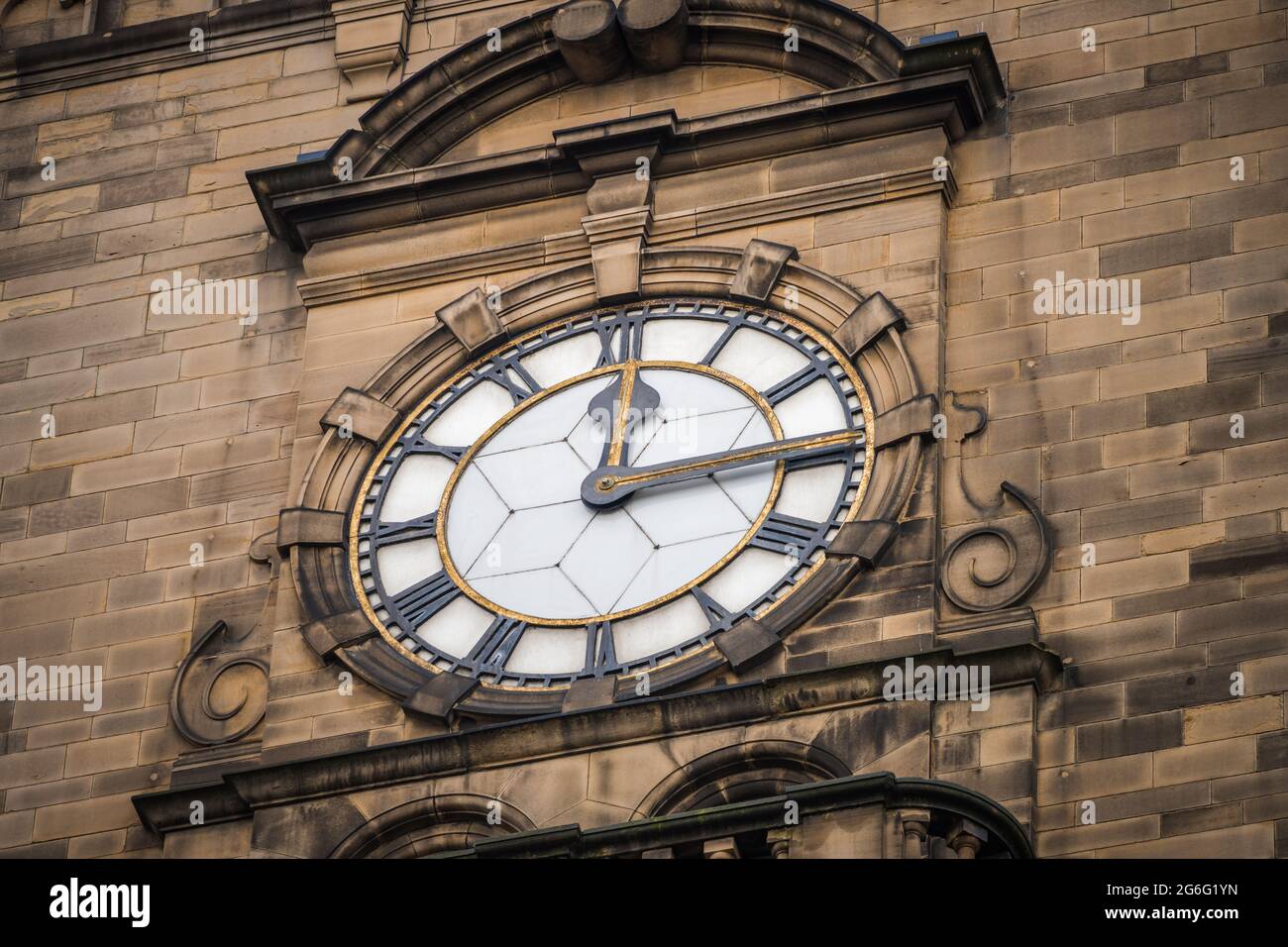 Viertel nach zwölf 12:15 Uhr Zifferblatt zeigt die Zeit mit römischen Ziffern auf historischen alten Steingebäude. Fünfzehn Minuten nach zwölf Uhr. Stockfoto