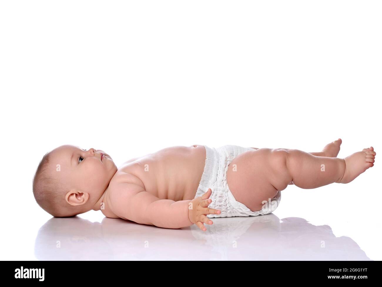 Kleinkind Baby Mädchen Kind in Windel liegt auf dem Rücken seitlich an der Kamera, schaut nach oben und hält ihre Beine nach oben Stockfoto