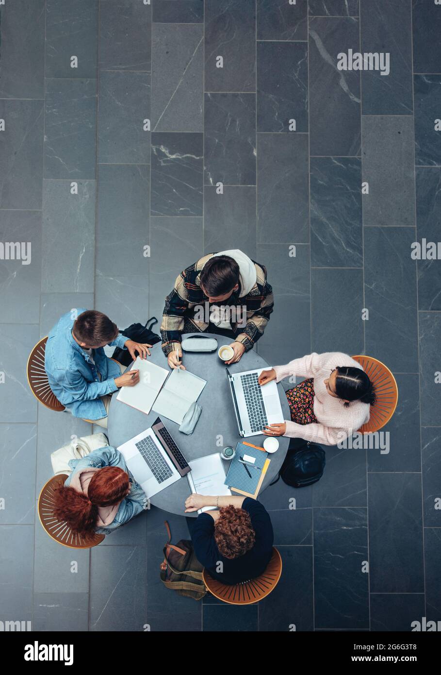 High-Angle-Ansicht eines Studenten in Zusammenarbeit mit seinem akademischen Auftrag. Draufsicht von jungen Menschen, die gemeinsam an einem Tisch studieren. Stockfoto