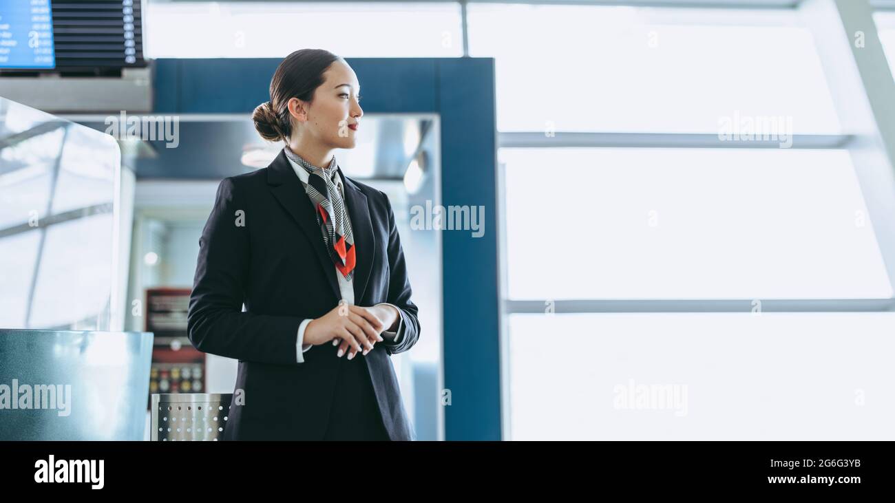 Seitenansicht des Flugbegleiters, der am Flughafen steht. Bodenpersonal wartet auf Passagiere am Flughafen. Stockfoto