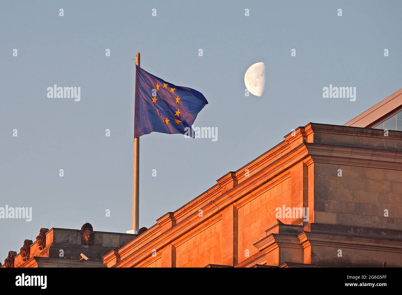 Im ersten Morgenlicht winkende europäische Flagge auf dem Reichstag mit Mond, Deutschland, Berlin Stockfoto