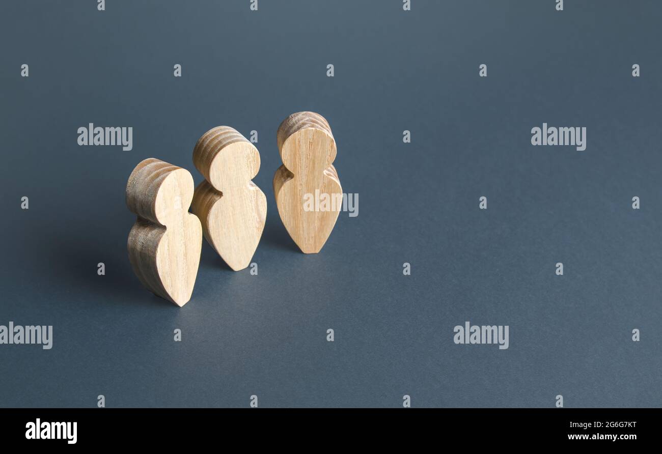 Drei menschliche Holzfiguren auf grauem Hintergrund. Kommunikation und Diskussion. Social Meeting. Unterstützung, Zusammenarbeit und Zusammenarbeit. Stockfoto