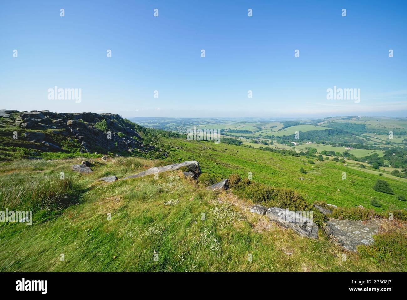 Die steilen, mit Felsbrocken übersäten Hänge von Baslow Edge hinunter und durch eine neblige, dunstige Landschaft in Derbyshire Stockfoto