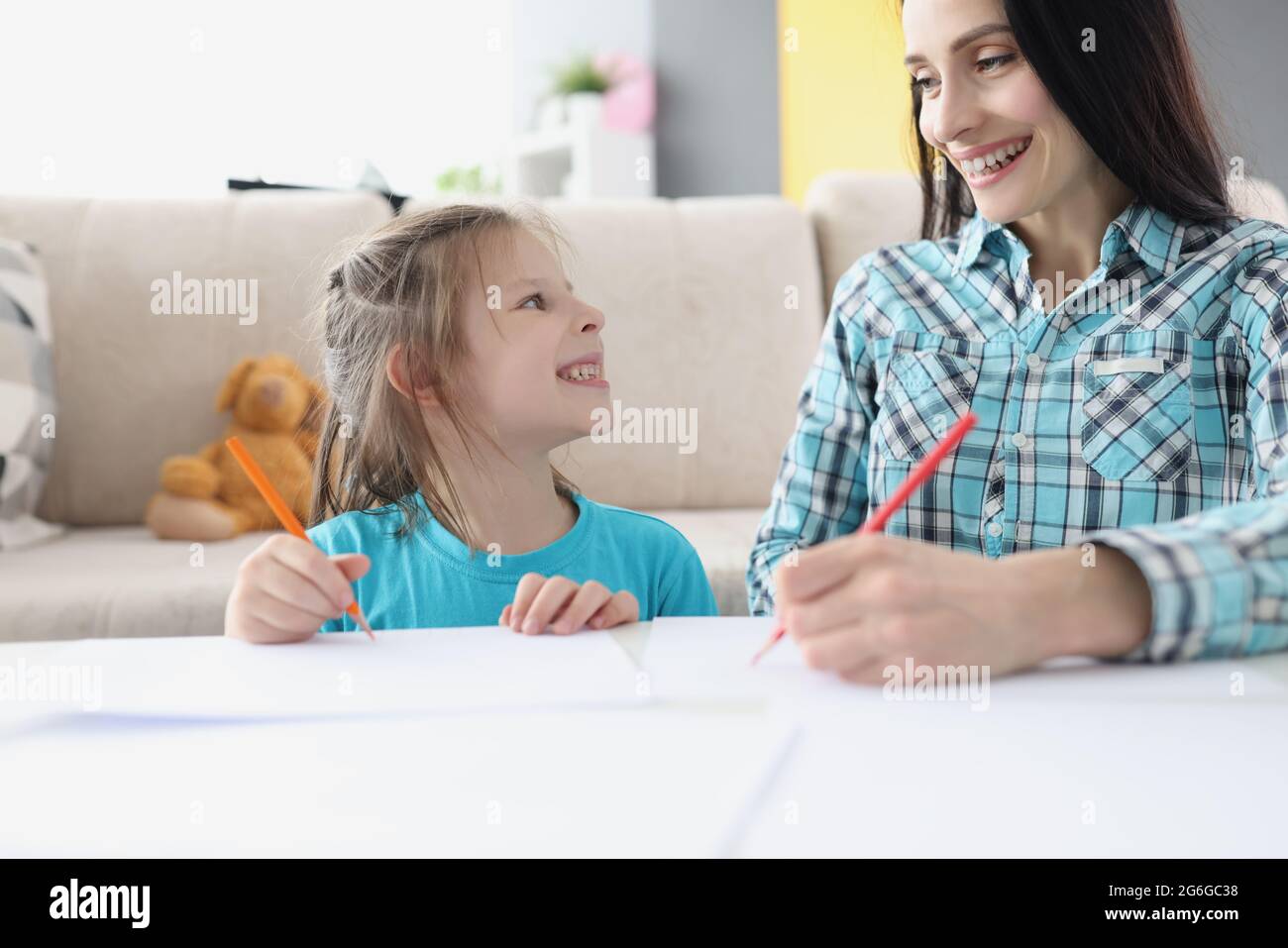 Glückliche Mutter und Tochter zeichnen mit Bleistiften auf Papier Stockfoto