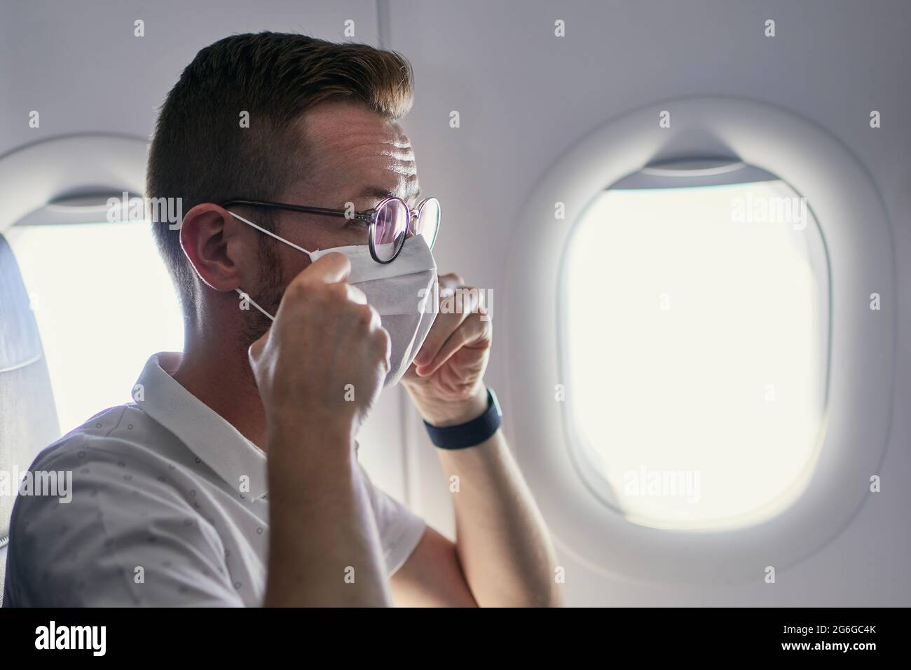 Passagier trägt eine Gesichtsschutzmaske im Flugzeug. Themen, die während der Pandemie-Covid-19 in neuem normalen und persönlichen Schutz unterwegs sind. Stockfoto