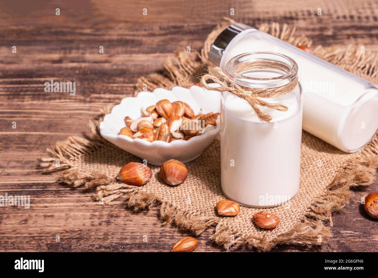 Hausgemachte vegane geröstete Haselnussmilch in einem Glas. Nicht-Milchprodukte gesundes Produkt, alter Holztisch. Modernes hartes Licht, dunkler Schatten, Kopierraum Stockfoto
