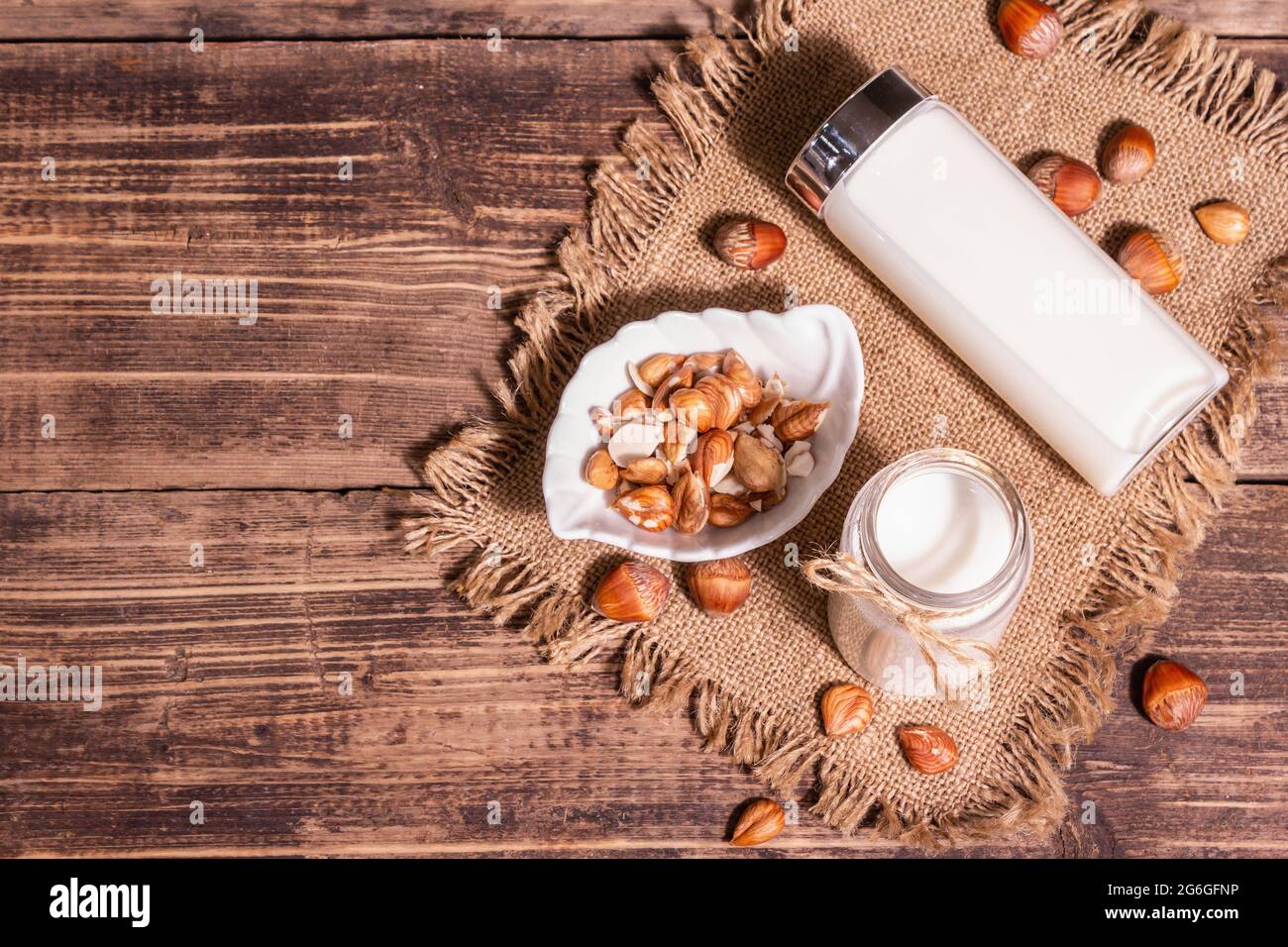 Hausgemachte vegane geröstete Haselnussmilch in einem Glas. Nicht-Milchprodukte gesundes Produkt, alter Holztisch. Modernes hartes Licht, dunkler Schatten, Draufsicht Stockfoto