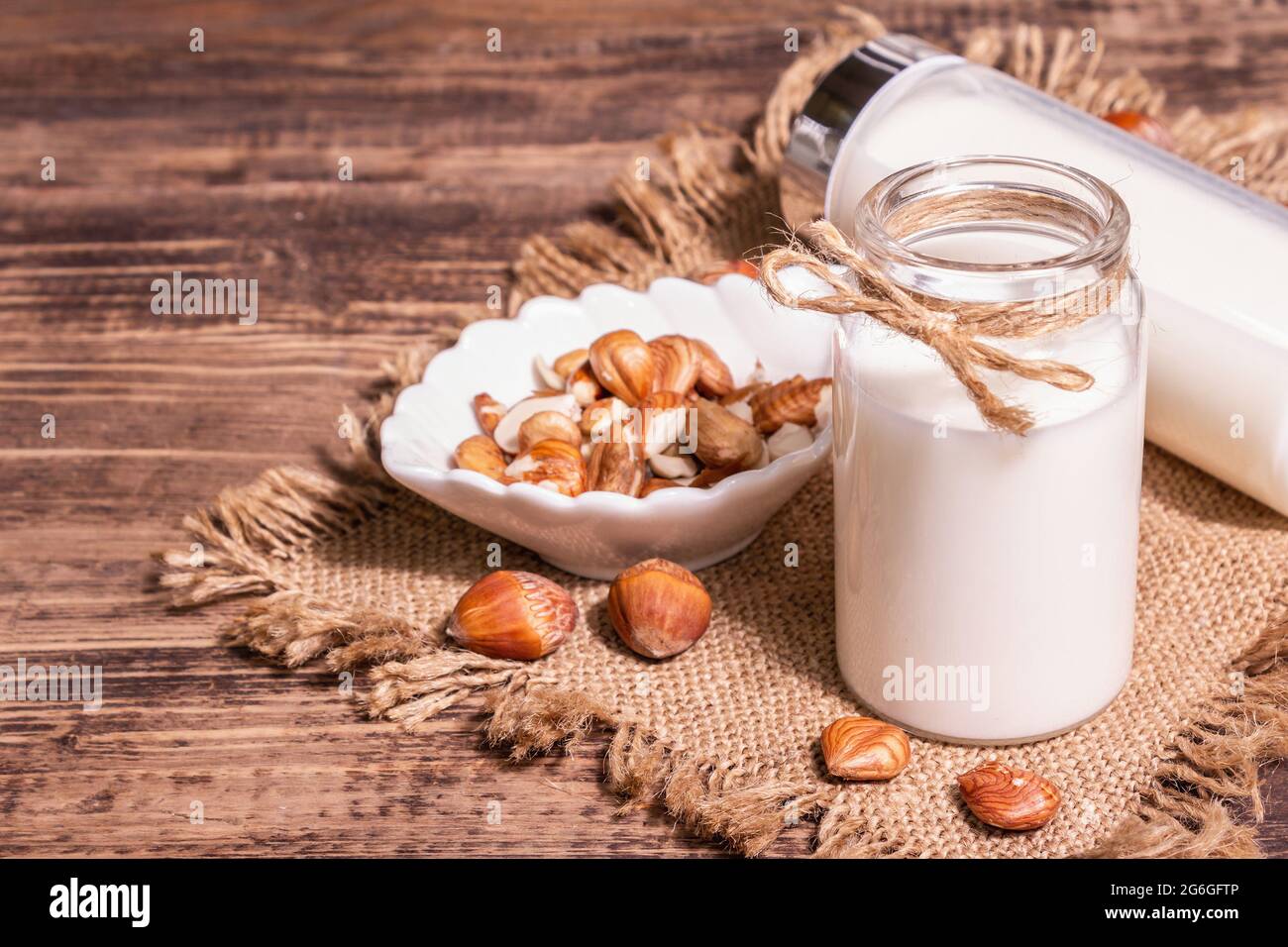 Hausgemachte vegane geröstete Haselnussmilch in einem Glas. Nicht-Milchprodukte gesundes Produkt, alter Holztisch. Modernes hartes Licht, dunkler Schatten, Kopierraum Stockfoto
