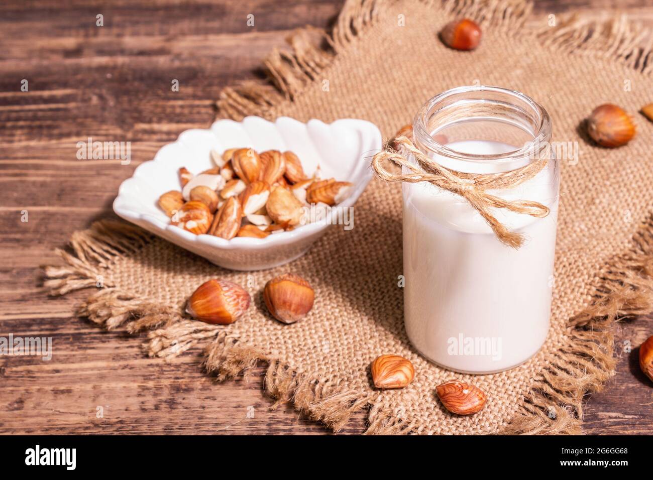 Hausgemachte vegane geröstete Haselnussmilch in einem Glas. Nicht-Milchprodukte gesundes Produkt, alter Holztisch. Modernes hartes Licht, dunkler Schatten, Kopierraum Stockfoto