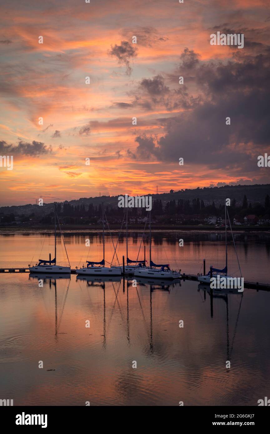 Segelyachten, die bei Sonnenuntergang in einem ruhigen Hafen auf einem Ponton festgemacht haben. Stockfoto