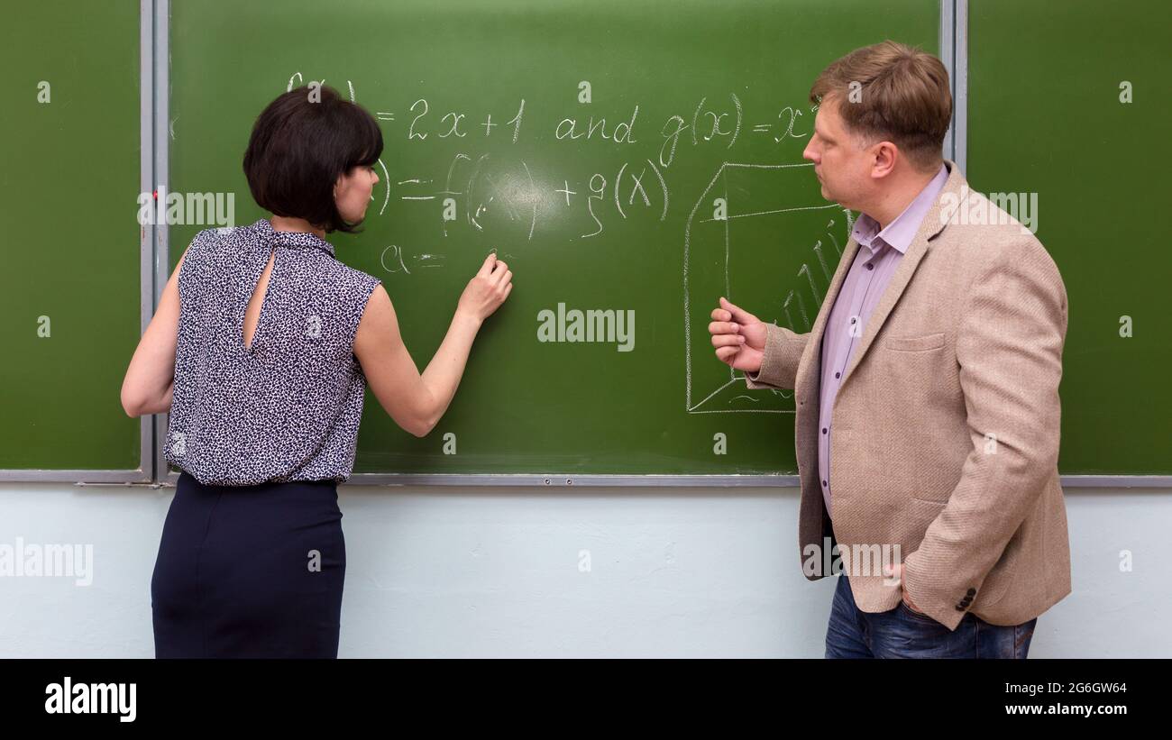 Der Lehrer erklärt dem Schüler die Lösung eines mathematischen Problems an der Tafel. Stockfoto
