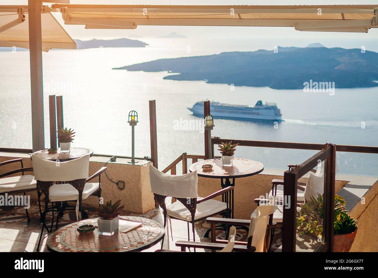Auf der griechischen Insel Santorini wird ein Esstisch mit Meer- und Berglandschaft, Blick auf den Vulkan und einem Schiff serviert. Stockfoto