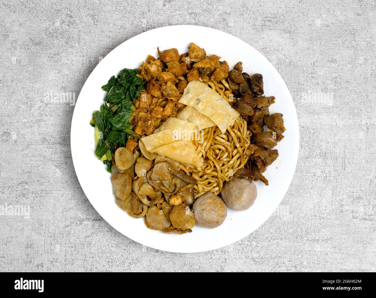 Lecker und lecker Mie ayam oder Mie Yamin oder Yamin Noodle mit Hühnerfleisch, Gemüse, Pangsit Goreng, Pangsit Rebus und Fleischbällchen auf weißem Teller Stockfoto