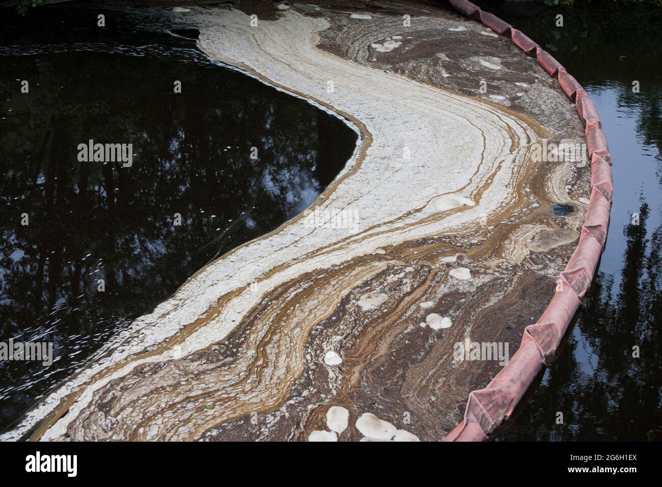 SAMMELT VERSCHMUTZUNG durch Ausleger im Wasserlauf der Papierfabrik Stockfoto