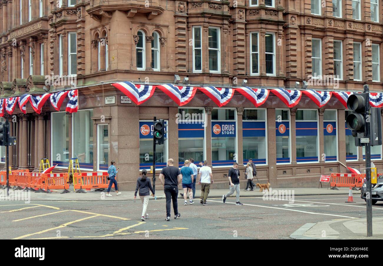 Glasgow, Schottland, Großbritannien, 6. Juli 2021. UK Weather: Letzte Vorbereitungen für die Dreharbeiten in der St vincent Street für die Dreharbeiten zum Mystery Blockbuster, der ein Vermögen gekostet hat, den Standort im Stadtzentrum entlang seiner Länge vorzubereiten und die Kameras morgen einzuziehen. Amerikanische Flaggen und Präsidentenanstacheln auf der New yorker Architektur mit der Umwandlung von lokalen Geschäften in manhattan hat zu Spekulationen über den indiana jones-Film geführt, aber das neueste Gerücht ist, dass das neue Fledermaus-Handy aufgrund der Größe von die Länge der Straße hochlaufen wird Die Lage. Quelle: Gerard Ferry/Alamy Live News Stockfoto