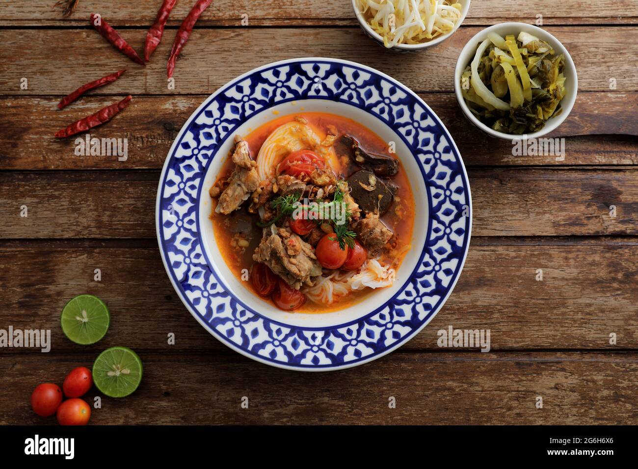 Lokale nordthailändische Küche Reisnudeln mit Schweinefleisch in würzigen Suppe im Holzhintergrund Stockfoto