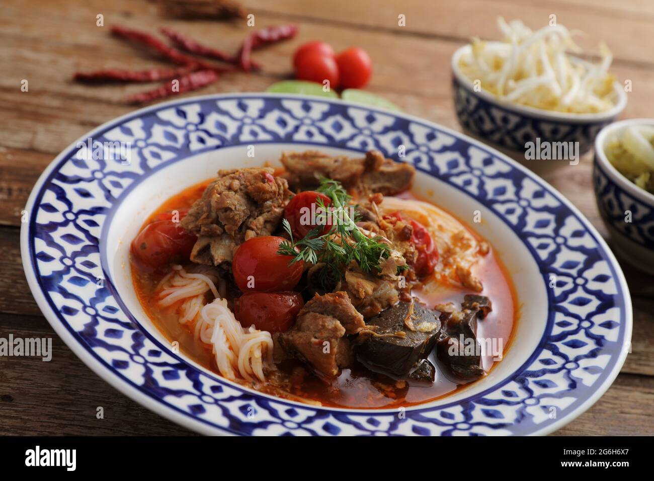 Lokale nordthailändische Küche Reisnudeln mit Schweinefleisch in würzigen Suppe im Holzhintergrund Stockfoto