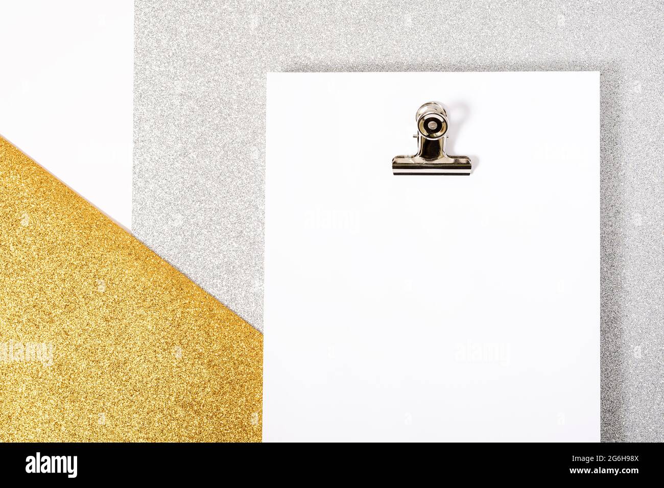 Weißes Folienpaket und Büroklammer auf einem Gold- und silbernen texturierten Hintergrund.das Foto hat Kopierraum, es wird von einem Overhead-Standpunkt aus genommen und ist Stockfoto