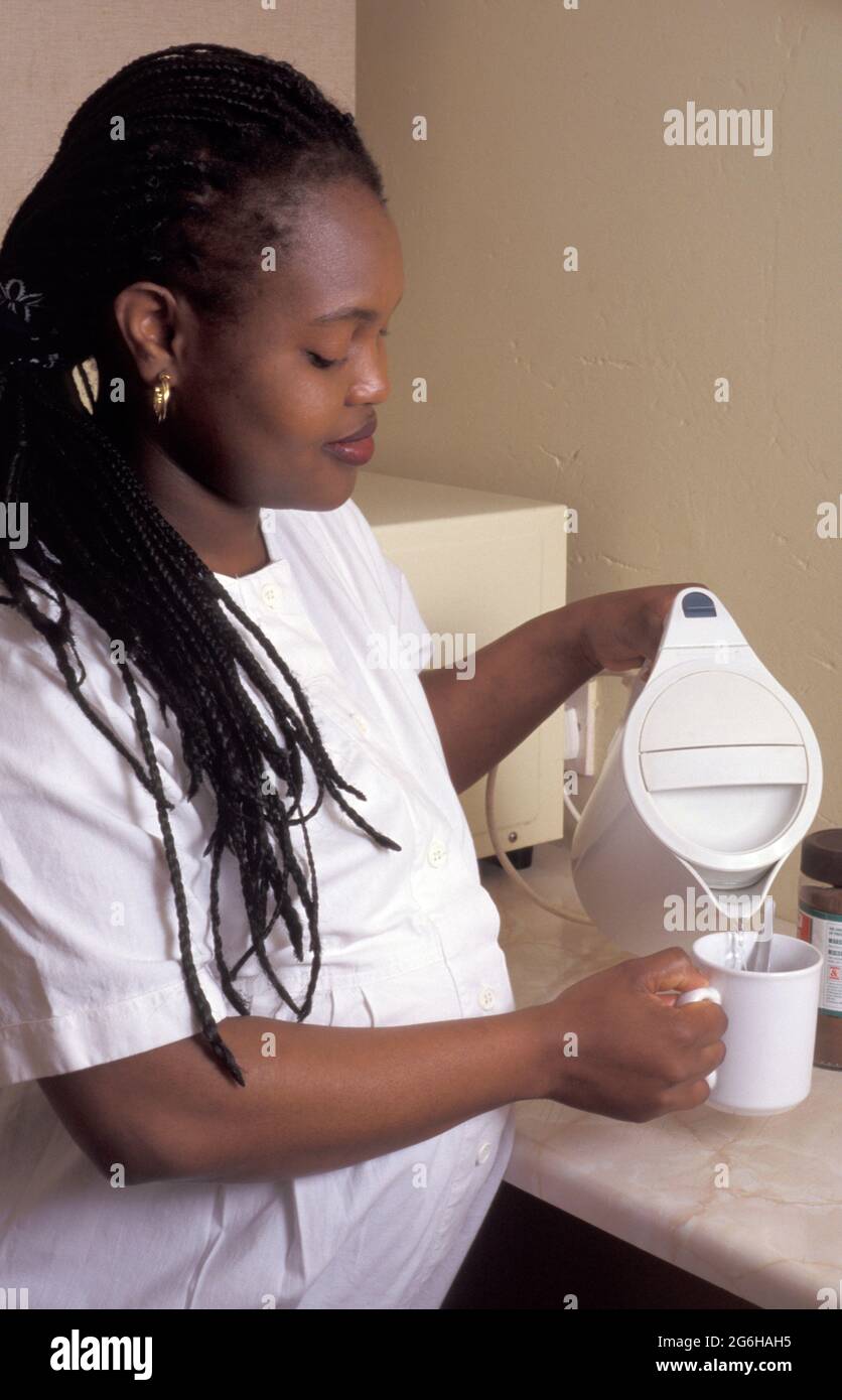 Hochschwanger afrikanische Frau gießt kochendes Wasser in den Becher Stockfoto