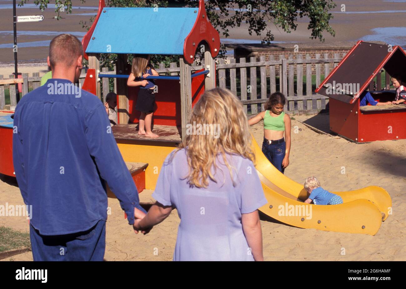 Junges Paar, das Kinder auf dem Spielplatz beobachtet Stockfoto