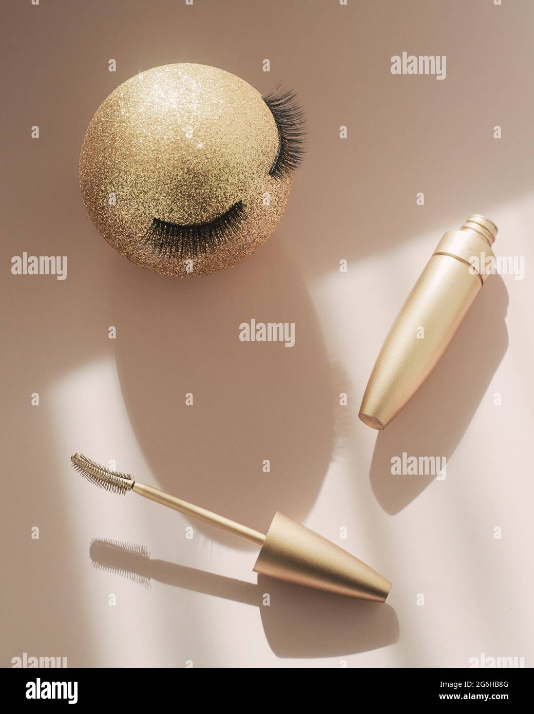 Mascara und ein goldener Weihnachtsball mit falschen Wimpern. Das Konzept der festlichen Make-up für Frauen. Make-up Artist Services Stockfoto