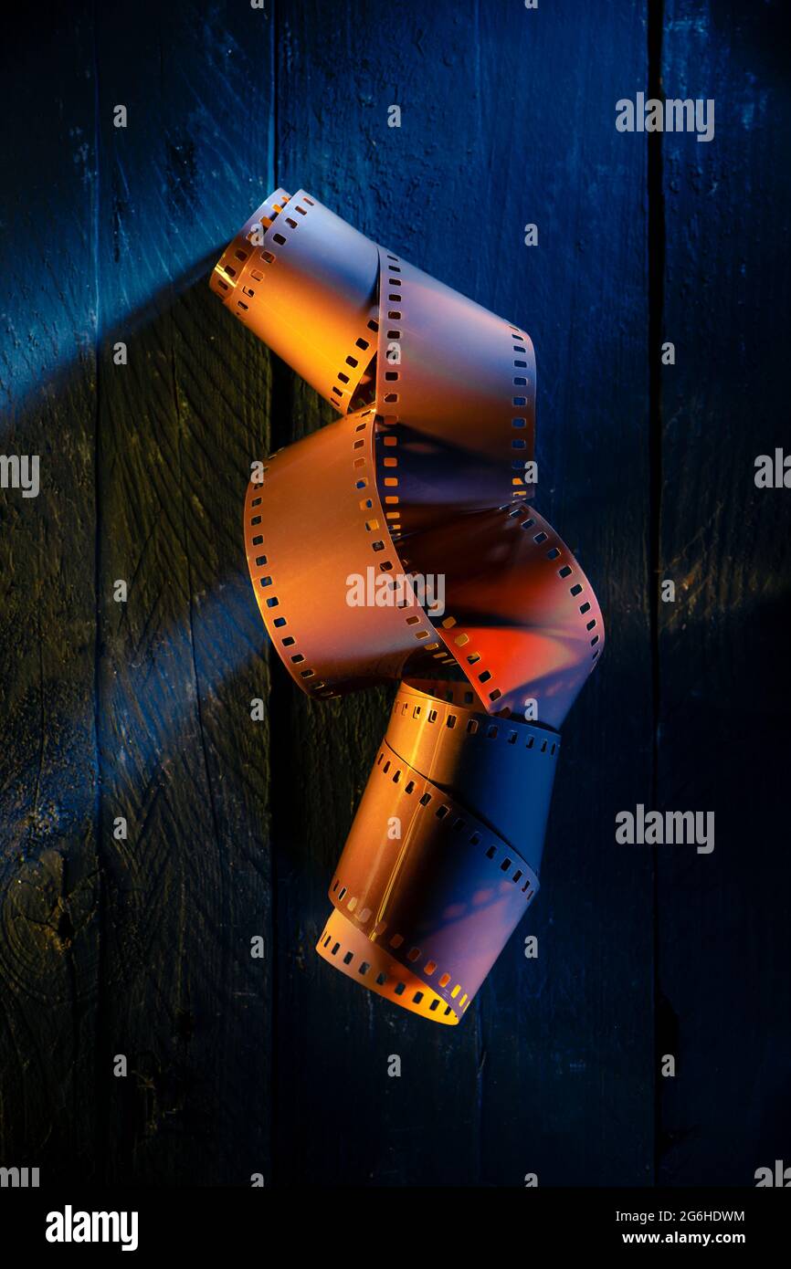 Farbfilm-Rolle auf schwarzem Holz mit farbigen Lichtern Stockfoto