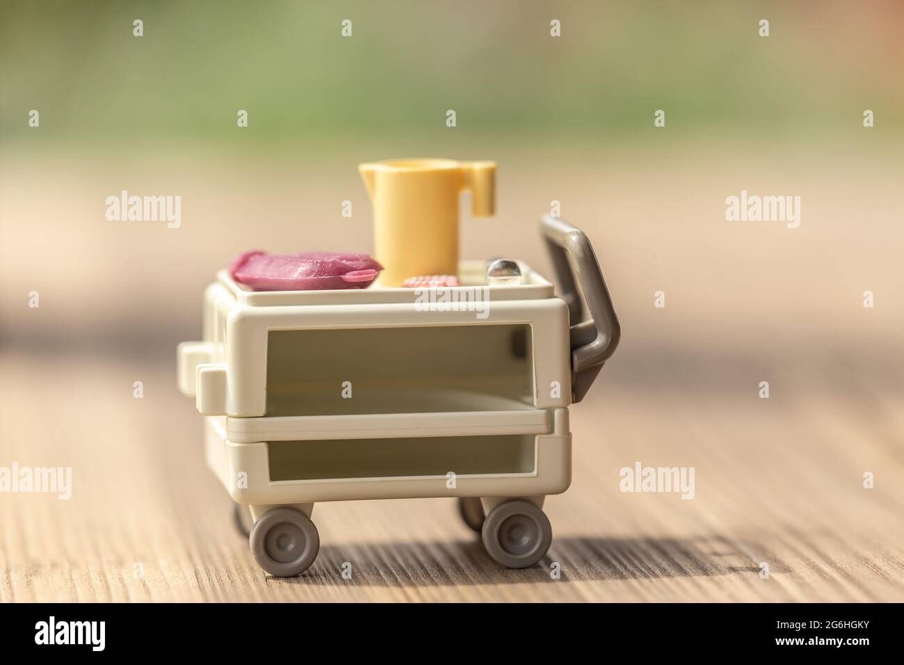 Pflegeszenerie mit Spielzeug nachjustiert: Eine Wärmflasche, eine Zahnplatte und eine Spritze auf einem medizinischen Trolley Stockfoto