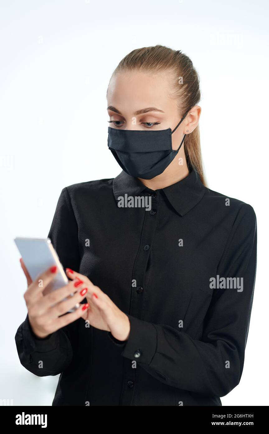 Frau in Gesichtsmaske mit Smartphone isoliert auf weißem Studio-Hintergrund Stockfoto