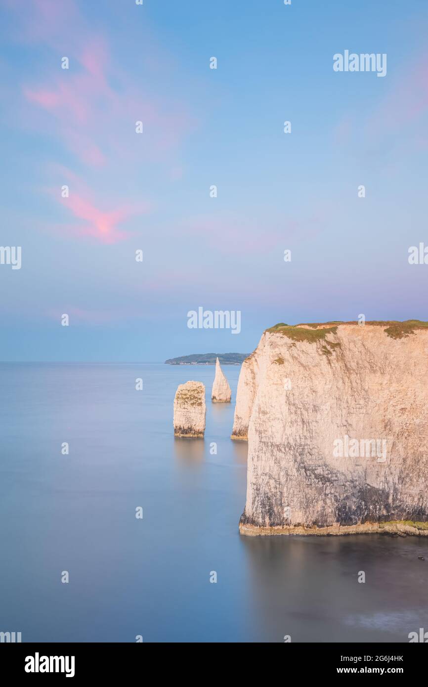 Farbenfrohe, idyllische Sonnenuntergangs- oder Sonnenaufgangshimmel über der Seenlandschaft der weißen Kreidefelsen und der Meeresstapel der Old Harry Rocks an der Jurassic Coast in Stockfoto