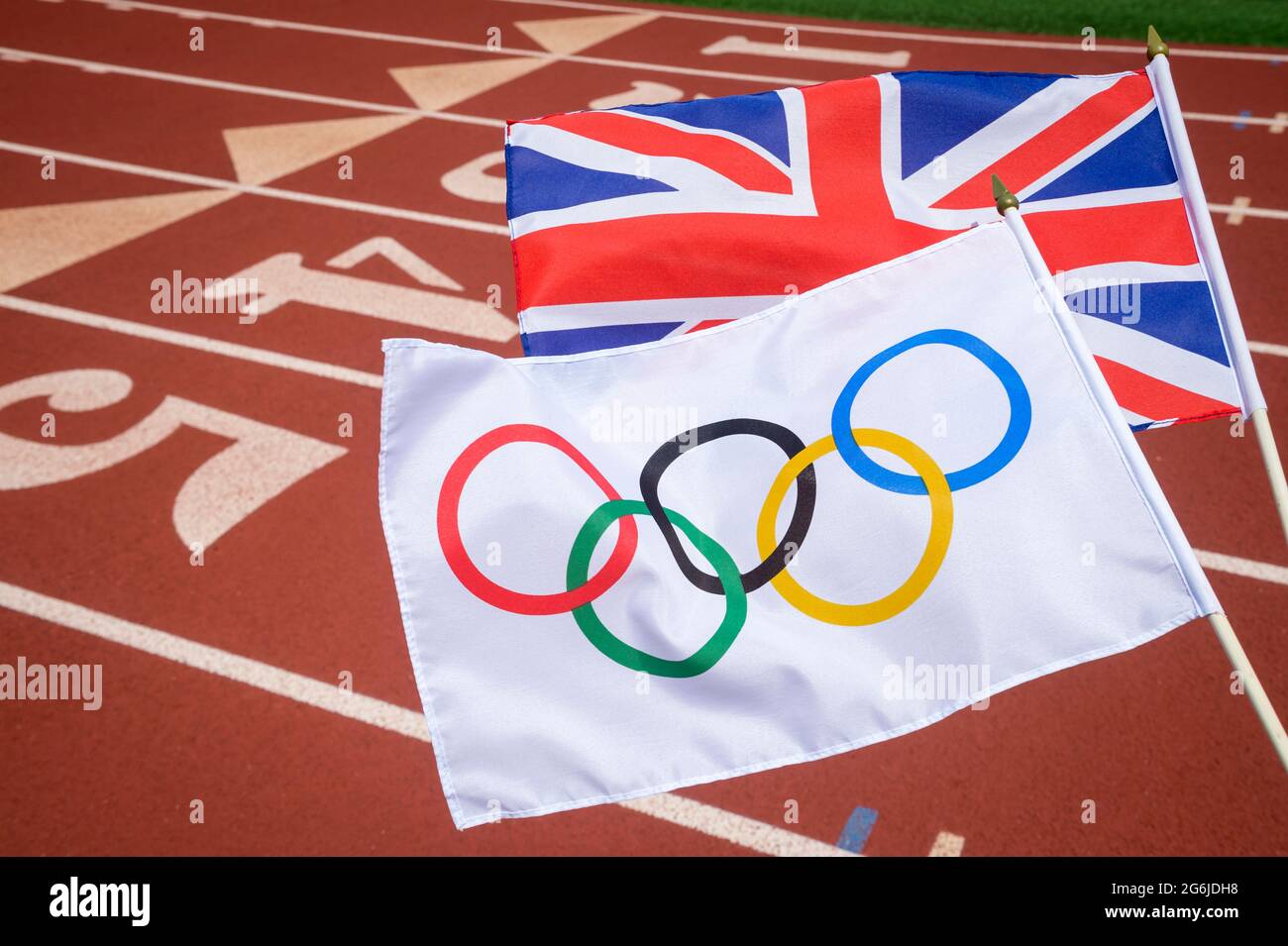 MIAMI, USA - AUGUST 2019: Eine olympische und eine britische Gewerkschaftsflagge flattern über der Startlinie einer roten Leichtathletik-Strecke zusammen. Stockfoto