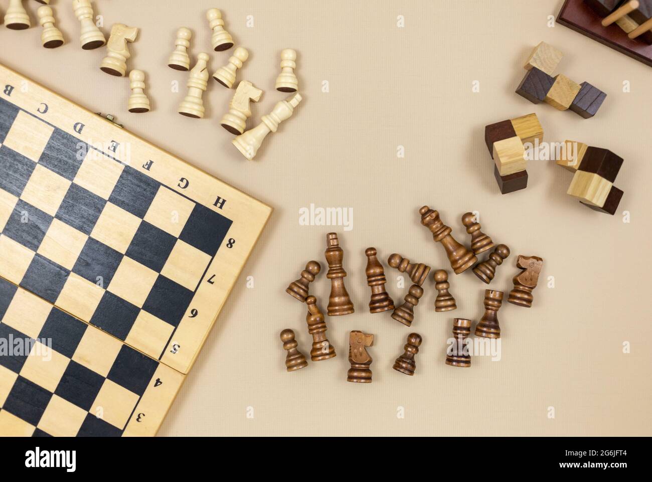 Schachbrett und Schachfiguren, Holzwürfel, Puzzle-Spiele auf beigem Hintergrund. Beliebte Logikspiele für logisches Denken. Stockfoto