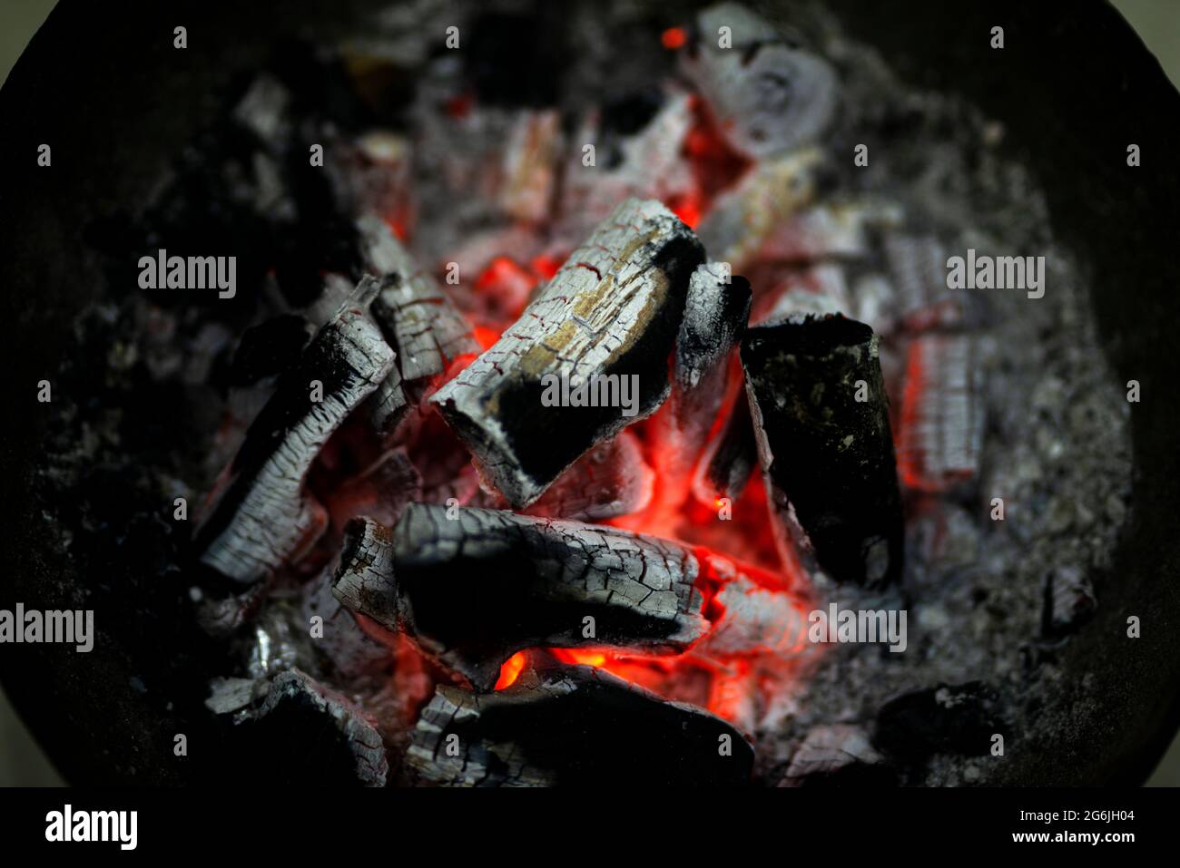 Verbrennung von Holzkohle in einem Eisenofen für die Heizung zu Hause. Rot verbrannte Holzkohle und Asche, um den Raum zu erwärmen. Stockfoto